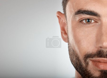 Foto de Face, beauty and eye of a man with clean, glow and healthy skin on a grey studio background for dermatology skincare. Portrait of a male with facial cosmetics for self care with marketing free space. - Imagen libre de derechos