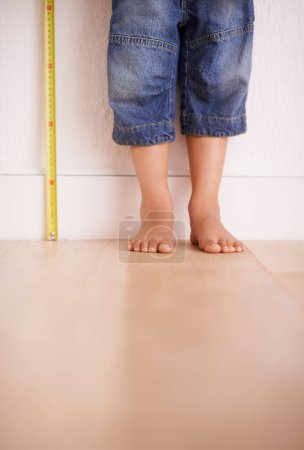 Photo for Hes grown right out of the frame. a young boy standing next to a tape measure - Royalty Free Image