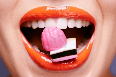 Téléchargez les photos : Licorice lips. a beautiful young woman eating liquorice sweets - en image libre de droit