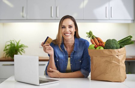 Foto de Making shopping a breeze. a young woman doing some online shopping with her groceries beside her - Imagen libre de derechos