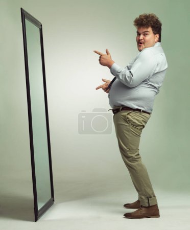 Photo for Im a sexy beast. an excited overweight man celebrating while looking in a mirror - Royalty Free Image
