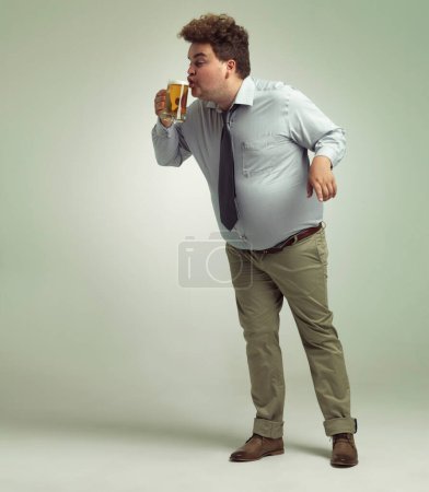 Téléchargez les photos : Bliss in that first sip. an overweight man sipping a pint of beer - en image libre de droit