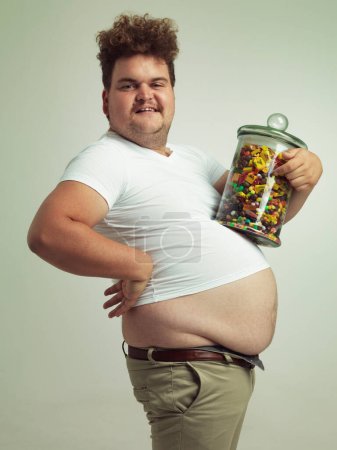 Téléchargez les photos : Meet my sweet little friend. an overweight man holding a large jar of candy - en image libre de droit