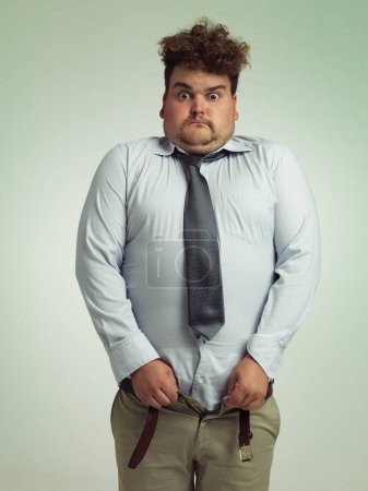Photo for Time to go on a diet. an overweight man sucking in his stomach to close his pants - Royalty Free Image