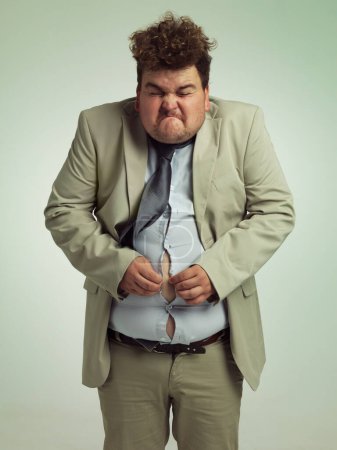 Photo for Time to go clothing shopping. an overweight man in a suit trying to close his shirt - Royalty Free Image