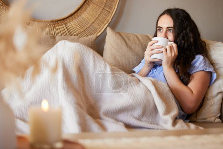 Woman with coffee, relax on sofa with peace and calm at home, wellness and morning routine. Content with coffee cup in living room, female chill with drink with satisfaction and self care.