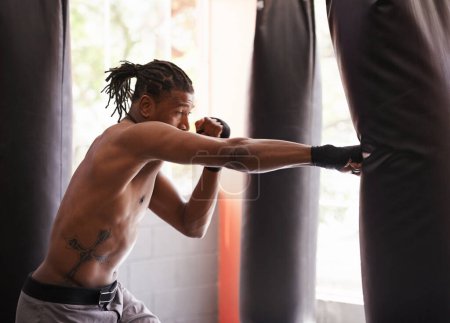 Photo for What a follow through. a young boxer working out on a heavy bag at a gym - Royalty Free Image