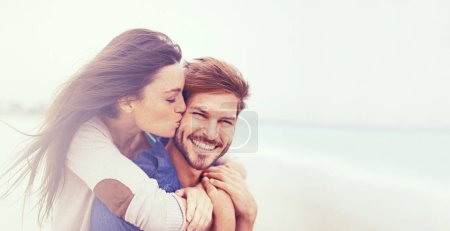 Photo for Indulging in some holiday romance. a young man giving his girlfriend a piggyback ride at the beach - Royalty Free Image
