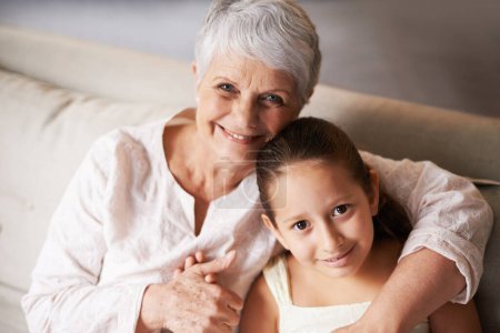 Photo for Time with granny. Portrait of a little girl and her grandma sitting on a sofa - Royalty Free Image