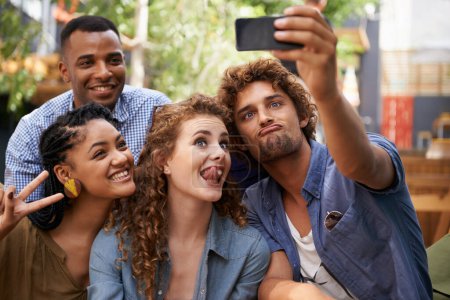 Photo for Capturing their moments of friendship. a group of friends taking a self-portrait on a cameraphone - Royalty Free Image