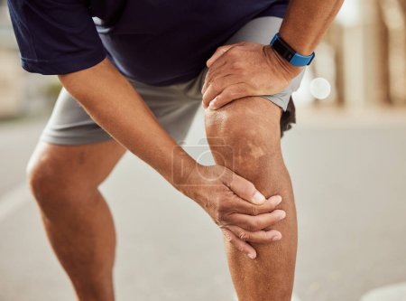 Foto de Fitness, knee pain and hands of black man with muscle ache, painful joint and injury after running in city. Sports, body wellness and male athlete rest after workout, marathon training and exercise. - Imagen libre de derechos
