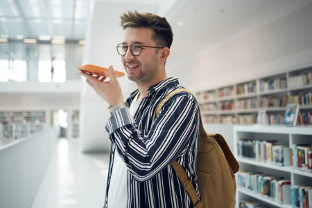 Man, phone call and speaker in library, smile and connection for communication, talking and planning study date. Young male, student or academic with smartphone, speaking or conversation in bookstore.