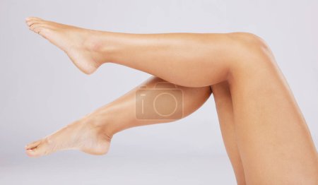 Photo for Skincare, legs and woman with cosmetics, wellness and clear skin against grey studio background. Leg, feet and female with smooth treatment, glow or shine with grooming, natural beauty or luxury care. - Royalty Free Image
