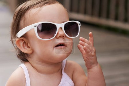 Photo for Loving Fashion from a young age. An adorable baby girl wearing oversized sunglasses outside - Royalty Free Image