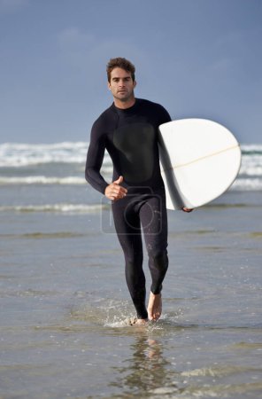 Photo for Driven to surf. Full length shot of a male surfer walking out of the water - Royalty Free Image