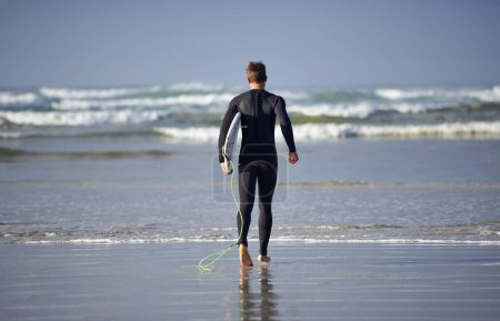 Photo for Ready to take on the waves. a young man about to go surfing - Royalty Free Image