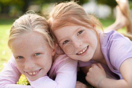 Téléchargez les photos : Sisters and best friends. Two little girls lying happily on the grass - en image libre de droit