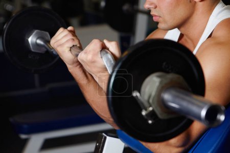 Photo for Hitting the weights. A young man lifting a dumbbell at the gym - Royalty Free Image