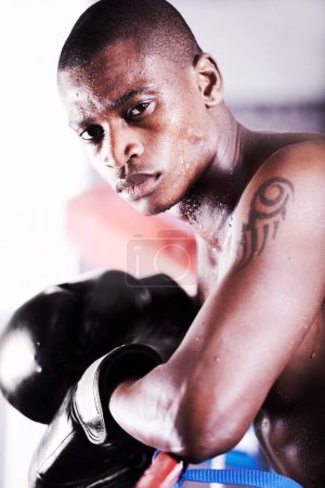 Téléchargez les photos : This is my passion and this is my life. An african american boxer leaning on the ropes and looking at you with resolve - en image libre de droit