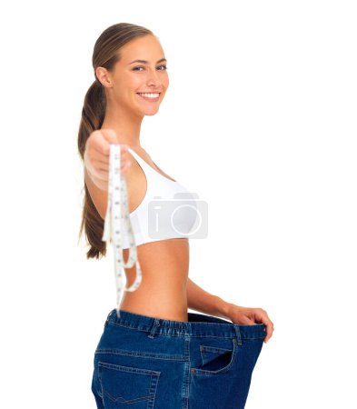 Foto de Diet, weightloss and happy woman with measuring tape, jeans and smile isolated on white background. Fitness, healthcare and wellness, woman with slim figure and liposuction skinny waist measurement - Imagen libre de derechos
