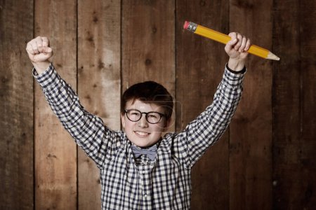 Foto de I can do it - Education. Young boy in retro clothing wearing spectacles and holding up a massive pencil - Imagen libre de derechos