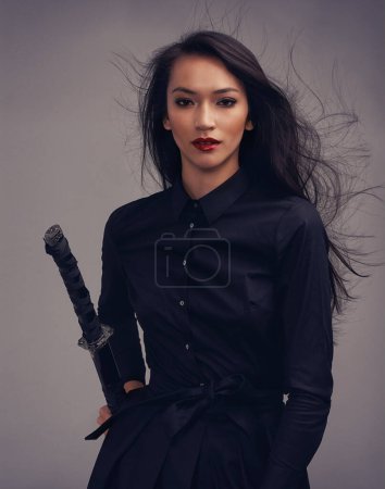 Téléchargez les photos : Fashion, beauty portrait and warrior woman art with sword to fight for power, cosplay and fantasy. Strong asian female from Japan in black for makeup and cosmetics for samurai or ninja battle. - en image libre de droit