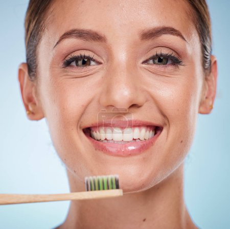 Téléchargez les photos : Brossage des dents, dentaire et femme avec brosse à dents pour le blanchiment des dents et la beauté, la santé buccodentaire et une haleine fraîche avec fond de studio. Bien-être buccal, portrait Invisalign et propre avec brosse en bambou - en image libre de droit