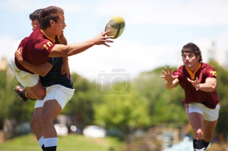 Photo for Team work is important to win. a young rugby player executing a pass mid-tackle - Royalty Free Image