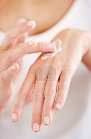Moisturizing her skin. Cropped image of a young woman applying cream to the back of her hand