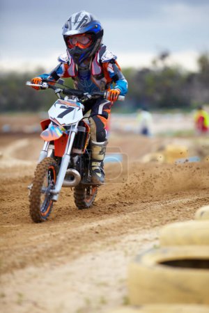 Photo for Hes way ehead of the pack. A young motocross rider coming round a bend on a track - Royalty Free Image