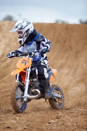 Photo for Looking ahead to the next bend. A young motocross rider coming down a hill on a dirt track - Royalty Free Image
