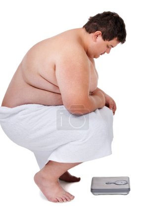 Téléchargez les photos : Not another pound...An obese young crouching dejectedly over a scale - en image libre de droit