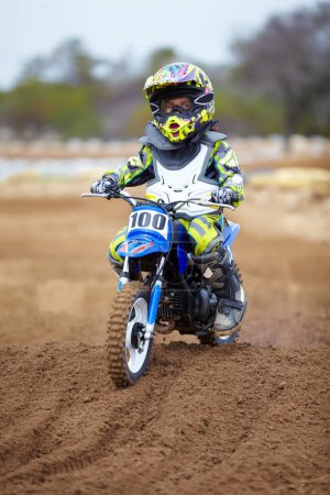 Photo for Youve gotta start young. A little boy riding a dirt bike on a track - Royalty Free Image