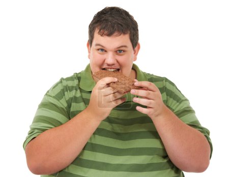 Photo for Does the body...no good. An obese young man looking at the camera and biting into a slab of chocolate - Royalty Free Image