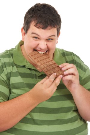 Photo for Chomping on his chocolate. An obese young man biting into a slab of chocolate against a white background - Royalty Free Image