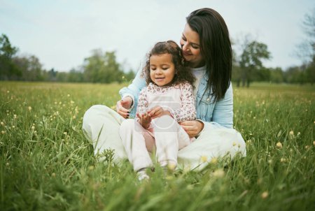 Téléchargez les photos : Children, family and field with a mother and girl sitting on grass together outdoor in nature during summer or spring. Kids, countryside and bonding with a mom and daughter in a green meadow. - en image libre de droit