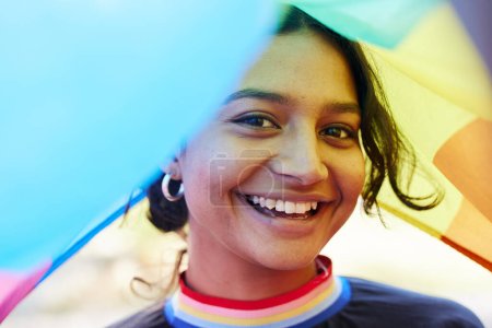 Rainbow, flag and portrait with an indian woman in celebration of lgbt equality, freedom or gay pride. Community, support or human rights with a gender neutral or non binary female celebrating lgbtq.