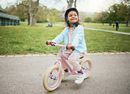 Foto de Cycling, thinking and child on a bike in the park, outdoor activity and learning in New Zealand. Sport, happiness and girl kid playing on bicycle ride in the neighborhood street or road in childhood. - Imagen libre de derechos