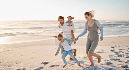 Foto de Carefree family playing on the beach together. Happy family on vacation by the ocean together. Little girls playing with their parents on holiday. Caucasian family bonding on the beach. - Imagen libre de derechos