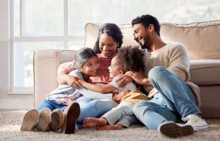Téléchargez les photos : Affectionate and loving mixed race family sitting together. Happy family with two daughters hugging their mother and bonding at home. Two little girls enjoying a happy childhood with mom and dad. - en image libre de droit