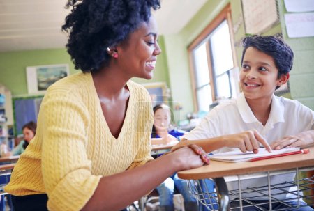 Photo for Education, learning and teacher help student with assignment in elementary school. Classroom support, scholarship and happy black woman or educator aid, explaining and helping boy learner in class - Royalty Free Image