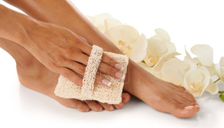 Téléchargez les photos : Feet, beauty spa and pedicure with a foot scrub for a woman in studio with flowers for luxury skincare. Toes and hands of wellness model for self care, cleaning and dermatology cosmetics in studio. - en image libre de droit