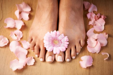 Foto de Feet, flower and spa pedicure with nails beauty of woman in studio for floral luxury skincare. Toes of wellness and beauty model for self care, cleaning and floral dermatology cosmetics in studio. - Imagen libre de derechos