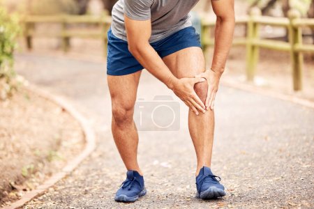 Foto de Not today, knee pain. an unrecognisable man experiencing knee pain while working out in nature - Imagen libre de derechos
