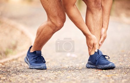 Téléchargez les photos : Am I not running right. an unrecognisable man experiencing ankle pain while working out in nature - en image libre de droit