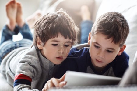 Téléchargez les photos : Children, bonding or tablet for movies streaming, brothers esports or social media on relax house sofa or home living room. Thinking, curious or kids on digital technology in education team learning. - en image libre de droit
