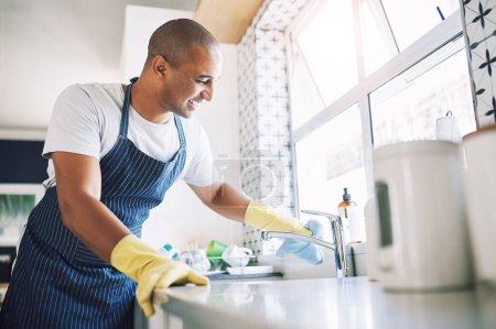 Photo for Keeping my space clean makes me feel good. a young man cleaning a kitchen at home - Royalty Free Image