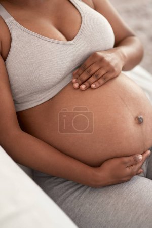Téléchargez les photos : Baby will be arriving sometime soon. Closeup shot of an unrecognisable woman touching her pregnant belly at home - en image libre de droit