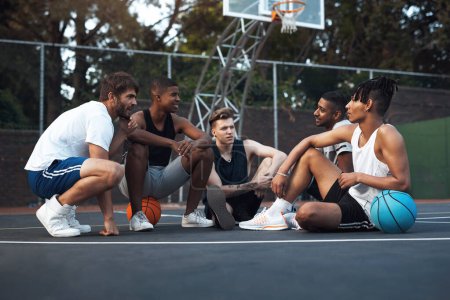 Foto de Conversing about one thing they all love - basketball. a group of sporty young men hanging out on a basketball court - Imagen libre de derechos