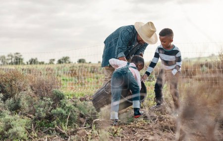 Foto de Learning about the value of hard work. a mature man working his adorable son and daughter on a farm - Imagen libre de derechos